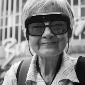Persona mayor sonriendo con las gafas de eyesynth en blanco y negro con fondo borroso