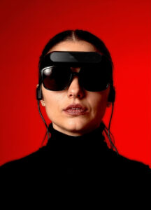 Mujer utilizando las gafas NIIRA de Eyesynth sobre fondo rojo, tecnología de asistencia para personas con discapacidad visual